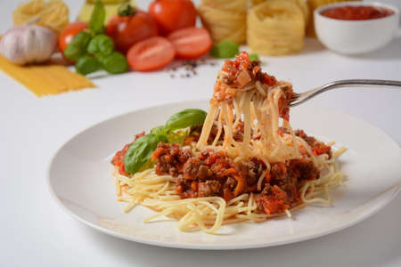 Traditional Italian spaghetti Bolognese  served on a white plate with tomatoes and basilの写真素材