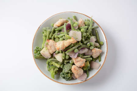 Frozen vegetable mixture of carrots, broccoli ,peppers, red onion and peas with pieces of cut chicken fillet. Healthy foodの写真素材