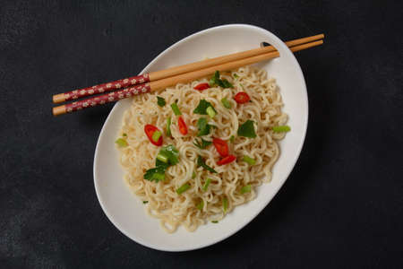 Bowl of instant noodles with chopsticks on black background.の写真素材