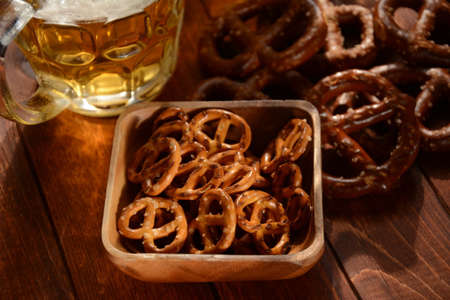 Hard Pretzels or Salted pretzels snack for party on rustic wooden table with glass of beerの写真素材