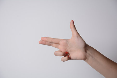 Girl's hand making shooting gun, gesture. hand pistol gesture on isolated white background. Girl hand pointing with two fingers.の写真素材