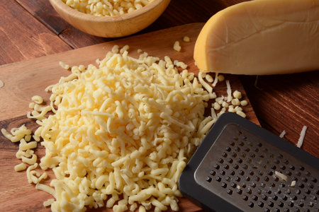 Heap of shredded cheese on small wooden board. Grated cheese for cooking on a cutting board on a...