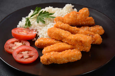 Chicken nuggets, rice and vegetables  on a black plateの写真素材