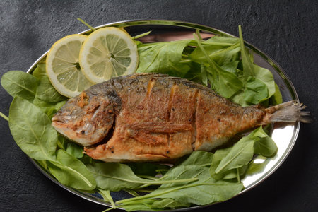 Fried fish dorado with fresh herbs and lemon on silver tray