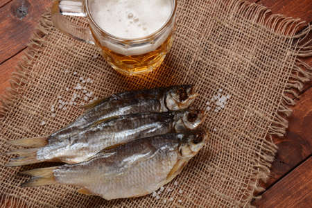 Salty dried fish roach and Beer mug with light foamed beer.の写真素材