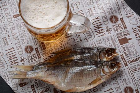 Salty dried fish roach and Beer mug with light foamed beer.の写真素材