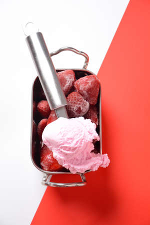 Frozen strawberries in silver bowl on white and redの写真素材