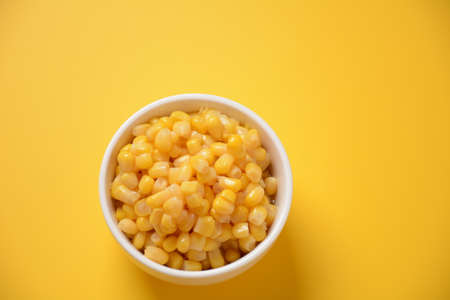 Bowl of sweet corn in white bowl  on yellow background
