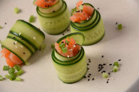 Cucumber rolls with pieces of salted salmon, black and white sesame seeds, chopped green onion. Holiday vegetable appetizersの写真素材