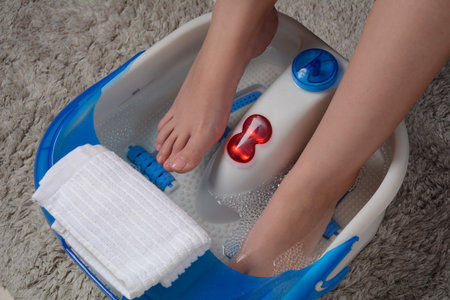 Female feet in a vibrating foot massager. Electric massage foot bath. Relax after work. Pedicure and foot careの写真素材