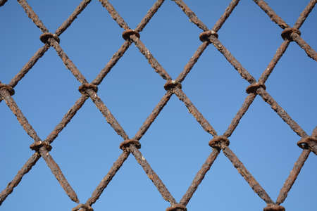 Forged rusty metal protective grille against blue skyの写真素材
