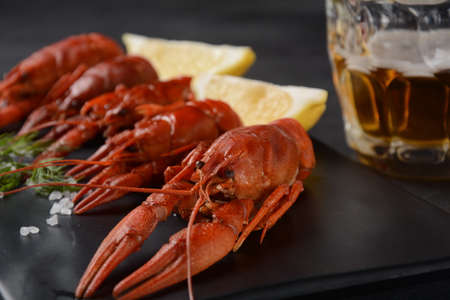 Red boiled crawfishes on table in rustic style. Asian Chinese Food Spicy Crayfish with a mug of beer.の写真素材