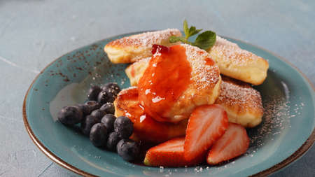 Cottage cheese fritters or syrniki or pancakes with fresh blueberries, strawberries and strawberry...