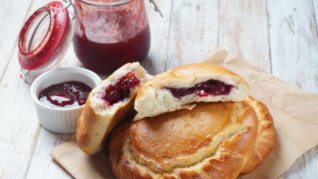 Cherry Pies stuffed with berries cherry, bowl with cherry jam. Homemade sweet pies from yeast dough...