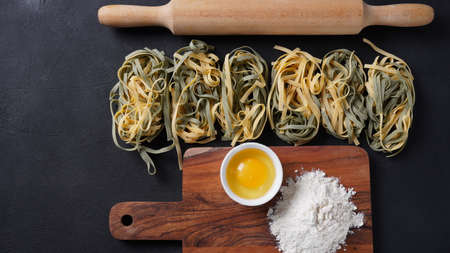Uncooked Italian homemade egg pasta with spinach placed side by sideの写真素材