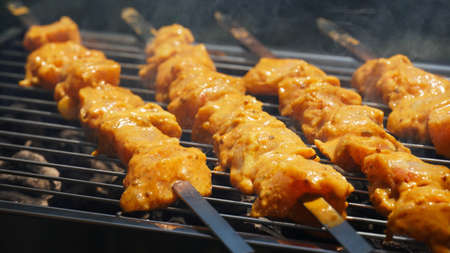 Shashlik - traditional Georgian barbecue. Closeup of raw roasted marinated meat barbecue shish kebab shashlik on steel metal skewers lying grill fire brazier with charcoal.  Making barbecueの写真素材