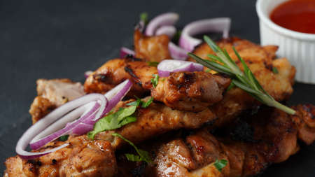 Grilled chicken breast  with sweet onions, herbs, sauce on stone black board. Traditional cuisine....