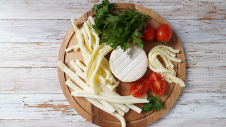 Camembert with String cheese or cheese whip - salty snack cheese with cherry tomatoes and herbs on...