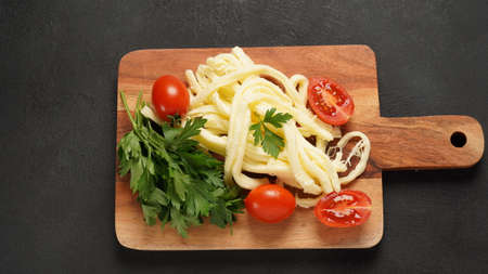 String cheese or cheese whip - salty snack cheese with cherry tomatoes and herbs on chopping board. Turkish cheeseの写真素材