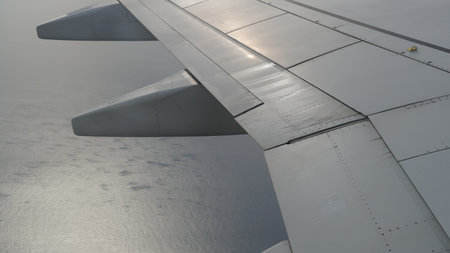 Wing of an airplane, passenger s view. Looking through the window of a plane on its shining wingの写真素材
