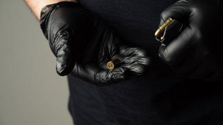 A man in a black T-shirt unload the pistol holder with 9 19 cartridges. Man`s hand holds  9 19mm pistol cartridgeの写真素材
