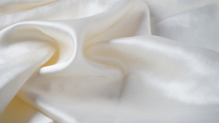 White silk fabric - soft, and delicate with shine, folds, creases. Smooth elegant silk  backgroundの写真素材