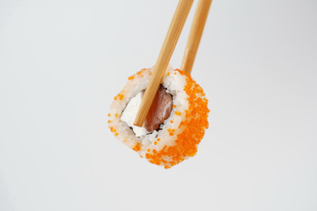 Sushi roll holding in eating sticks. Japanese traditional Cuisine