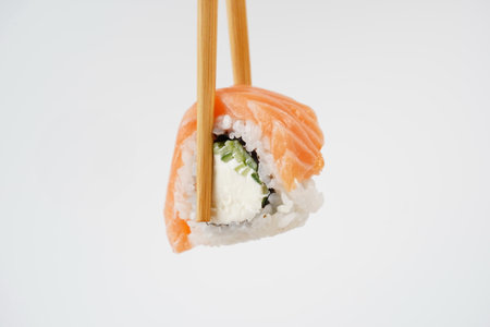 Sushi roll holding in eating sticks. Japanese traditional Cuisineの写真素材