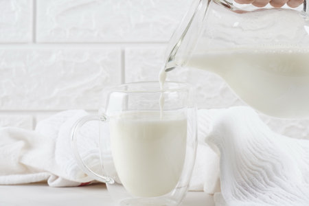 Woman pouring milk from a jar into the glassの写真素材