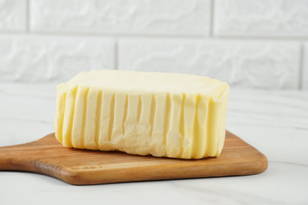 Block of fresh butter sliced on wooden cutting boardの写真素材