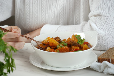 Young woman is eating traditional homemade Hungarian beef meat stew and soup  - Goulashの写真素材