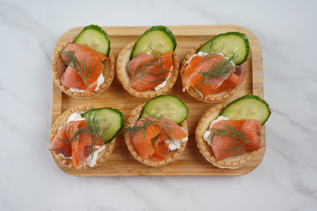 Tartlets with salmon, cheese, cucumber and dill. Tasty snacks with salted salmon and cottage cheese fillingの写真素材