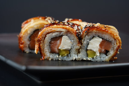 Unagi maki. Ð«ushi roll with eel on black plate on black backgroundの写真素材