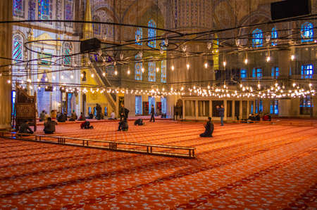The interior of Blue Mosque (Sultan Ahmed Mosque) with several people praying inside.のeditorial素材