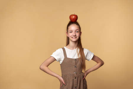 Smiling teenage girl with an apple on her head.の写真素材