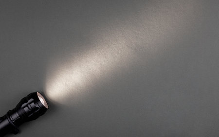 A bright beam of light from a flashlight shines on a gray background.の写真素材