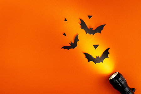 Orange cute Halloween background design with copy space with bats silhouettes and flashlight beam.の写真素材