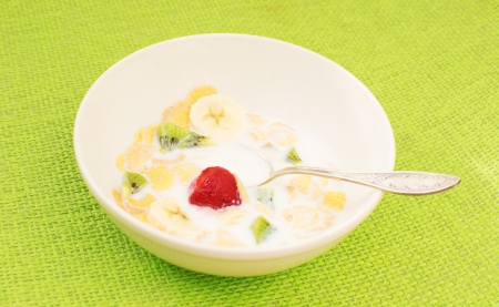 Breakfast cereal with milk and fruit in a white bowl with a silver spoonの写真素材