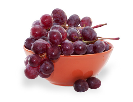 Branch of purple grapes in orange Bowl, isolated on white backgroundの写真素材