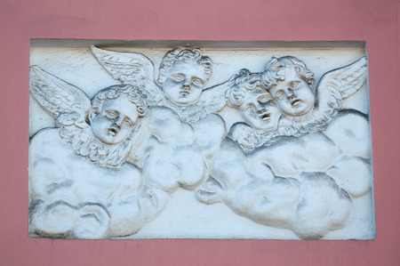 Old bas-relief figures of angels on front of  houseの写真素材