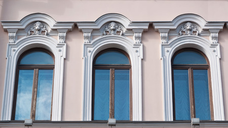 Fragment of building with three windows and eaves in the form of lions' headsの写真素材