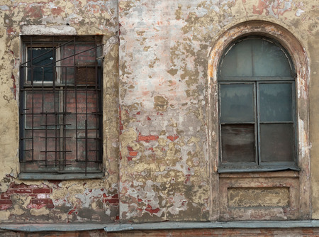 Two windows, one barred on background an old wall with plasterの写真素材