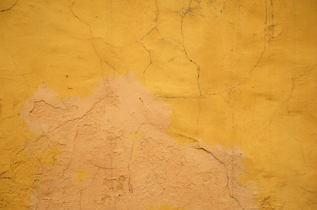 Texture of old rustic wall covered with yellow stuccoの写真素材