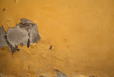 Texture of old rustic wall covered with yellow stuccoの写真素材