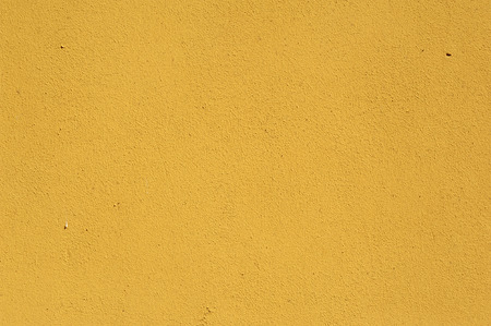 Texture of old rustic wall covered with yellow stucco