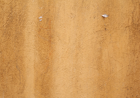 Texture of old rustic wall covered with yellow stuccoの写真素材