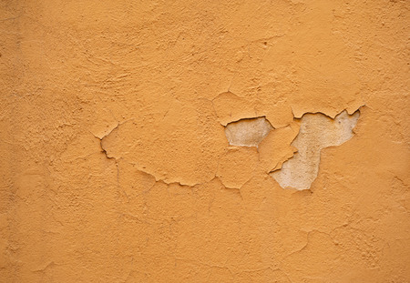 Texture of old rustic wall covered with yellow stuccoの写真素材