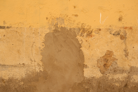 Texture of old rustic wall covered with yellow stuccoの写真素材