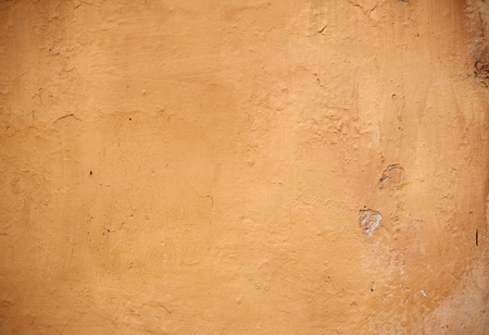 Texture of old rustic wall covered with yellow stuccoの写真素材