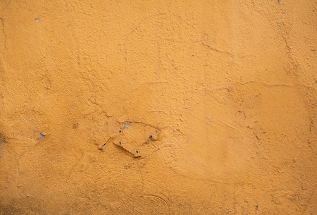 Texture of old rustic wall covered with yellow stuccoの写真素材